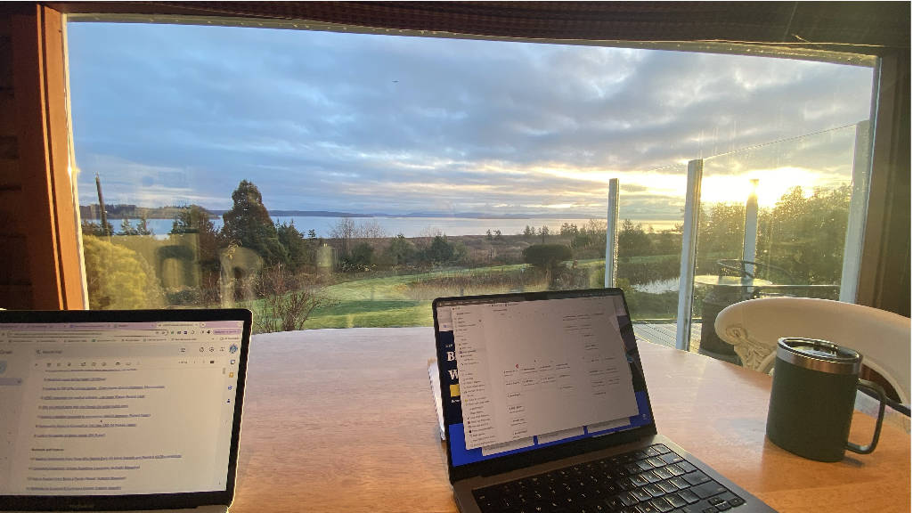 A picture of both of our laptops on a table looking out the window to a beautiful view. This was our work office for 9 days on a farm.