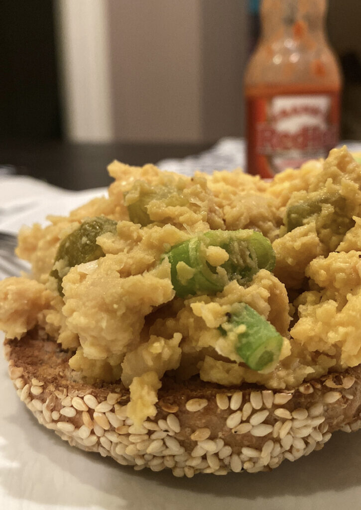 A picture of our tofu scramble on a bagel, something we love to cook while we're in a kitchen during out Trusted Housesitters stays.