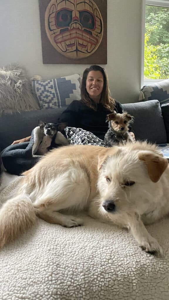 A picture of Donna on a couch with our dog Dewey as well as Oscar and Tiger, two dogs we care for often.